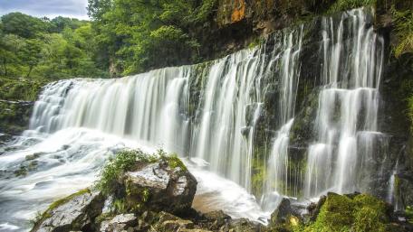 Majestic Waterfall Amidst Lush Greenery wallpaper