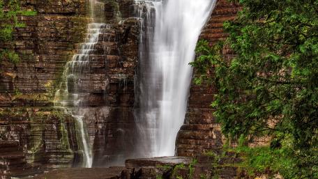 Majestic Waterfall Cascading Down Rocky Cliffs wallpaper