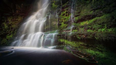 Serene Waterfall Cascading Down Mossy Rocks wallpaper