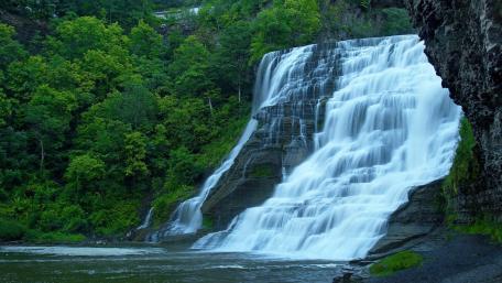 Serene Waterfall Cascading Through Lush Greenery wallpaper