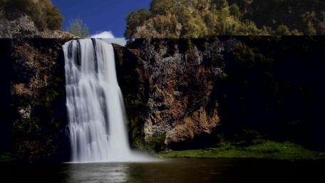 Majestic Waterfall Among Lush Greenery wallpaper
