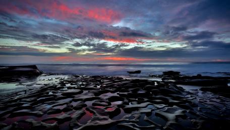 Stunning Sunset Over Rocky Shoreline wallpaper