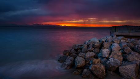 Vibrant Sunset Over Rocky Shoreline wallpaper