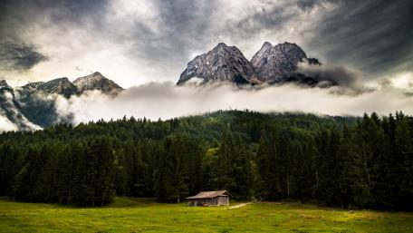 Serene Cabin Amidst Majestic Mountains wallpaper