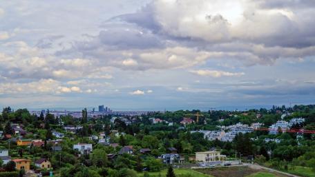 Serene Cityscape with Lush Greenery and Dramatic Clouds wallpaper
