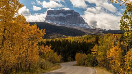 Golden Autumn Roadway Amidst Majestic Mountains wallpaper