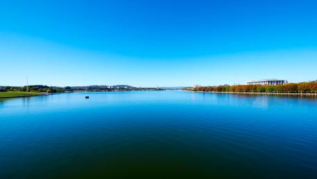 Serene Lakeside Landscape Under Bright Blue Sky wallpaper