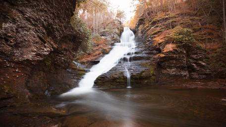 Majestic Waterfall in Serene Forest Setting wallpaper