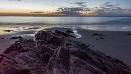 Serene Sunset Over Rocky Shoreline wallpaper