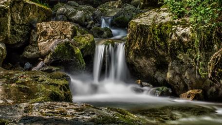 Serene Waterfall Amidst Lush Stones wallpaper