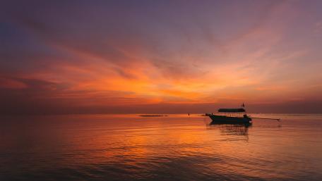 Serene Sunset Over Calm Waters And Boat wallpaper