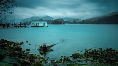 Tranquil Boathouse by the Lake Under Cloudy Skies wallpaper