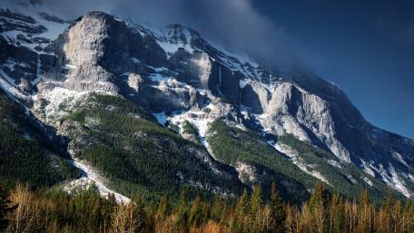 Majestic Mountain Ridge Surrounded by Lush Forests wallpaper