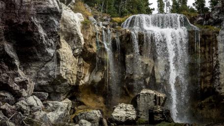 Majestic Waterfall Cascading Down Rocky Cliffs wallpaper