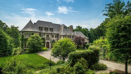 Elegant Mansion Surrounded by Lush Greenery and Blue Skies wallpaper