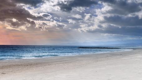 Serene Beach Under Cloudy Skies wallpaper
