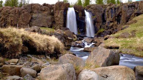 Majestic Waterfall Cascading Over Rocks in Nature's Embrace wallpaper