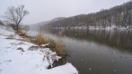 Winter River Scene with Gentle Snowfall wallpaper