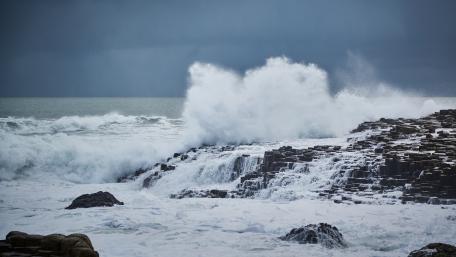 Powerful Waves Crashing on Rocks in a Stormy Sea wallpaper