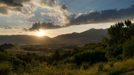 Golden Sunrise Over Silhouetted Mountains and Lush Greenery wallpaper