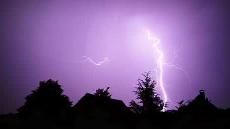 Purple Lightning Storm Over Distant Silhouettes wallpaper