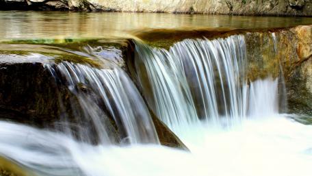 Serene Waterfall Cascading Over Rocks in Nature wallpaper