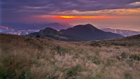Serene Dusk Over Rolling Hills and Ocean Lights wallpaper