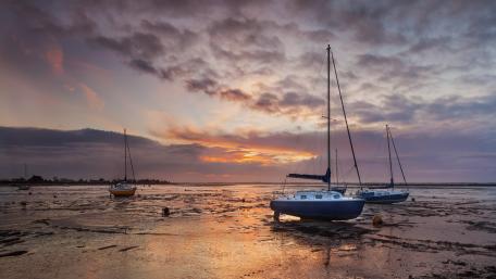 Serene Sunset Over Sailboats on the Shore wallpaper