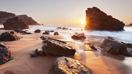 Golden Sunset Over Rocky Beach Scene wallpaper