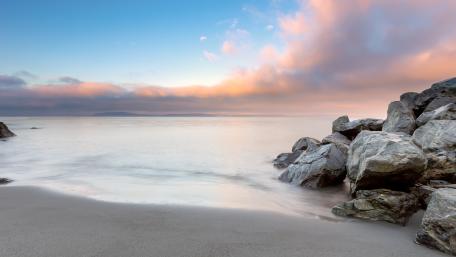 Serene Beach at Dusk with Boulders and Calm Sea wallpaper