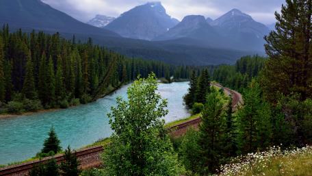 Tranquil Railway by Pristine River and Majestic Mountains wallpaper