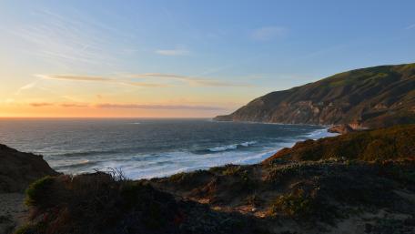 Serene Coastal Sunsets Overlooking Waves and Hillside wallpaper