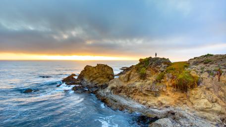 Serene Coastal Sunset Over Rocky Shoreline wallpaper