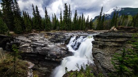 Majestic Waterfall Amidst Rocky Landscape wallpaper