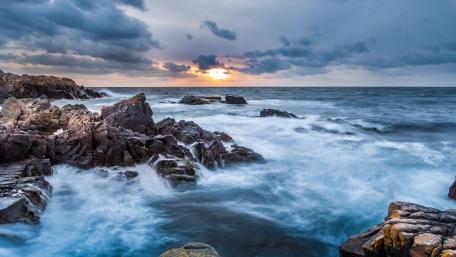 Serene Sunset Over Rocky Shoreline wallpaper