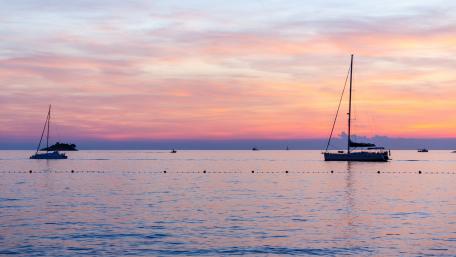 Tranquil Horizon with Sailboats and Pink Sky wallpaper