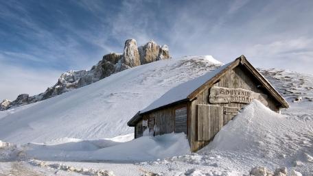 Winter Cabin Amidst Majestic Snowy Peaks wallpaper