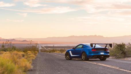 Blue Sports Car on an Open Desert Road at Sunset wallpaper
