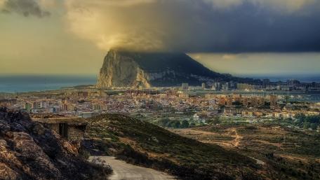Majestic Cityscape Under Cloudy Mountains wallpaper
