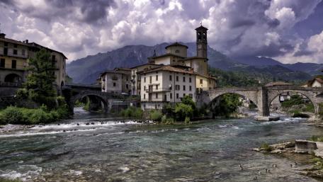 Serene Town by the River Under Dramatic Skies wallpaper