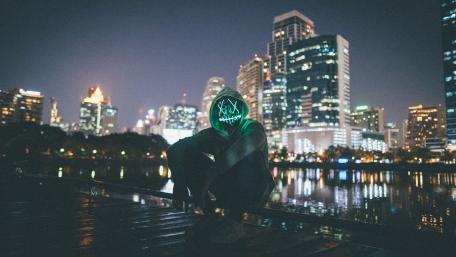 Neon Masked Adventurer in Cityscape at Night wallpaper