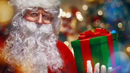 Festive Santa Holding Christmas Gift wallpaper