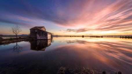 Serene Cottage at Sunset Over Calm Waters wallpaper