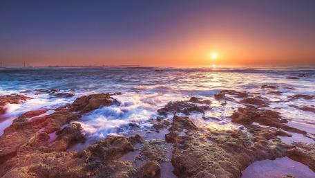Serene Sunset Over Rocky Shoreline wallpaper