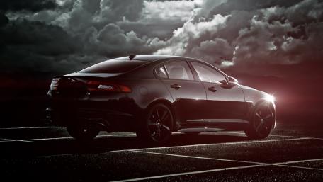 Sleek Black Car Under Dramatic Skies wallpaper