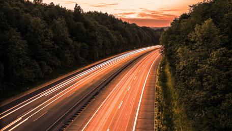Vibrant Light Trails on a Serene Highway at Sunset wallpaper
