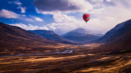 Breathtaking Hot Air Balloon Adventure Over Majestic Mountains wallpaper