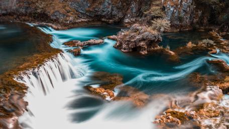 Serene Waterfall Flowing into a Tranquil Stream wallpaper