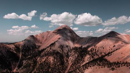 Majestic Peaks and Fluffy Clouds in Serene Skies wallpaper