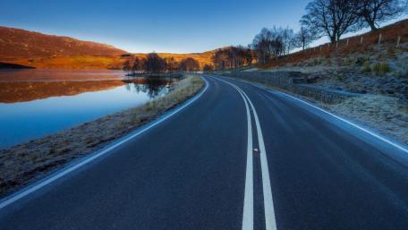 Tranquil Road Beside Serene Lake at Dusk wallpaper